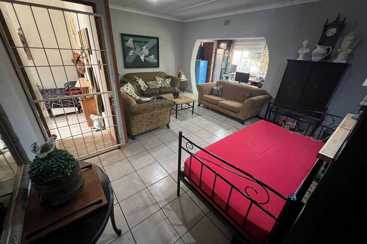 Spacious living area featuring tiled flooring, a distinctive arched opening leading to an adjacent room, and a secure metal gate entrance.
