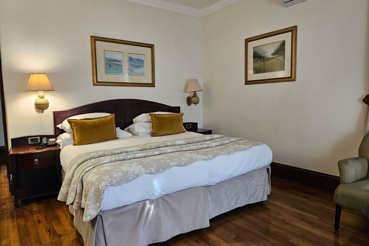 A well-maintained bedroom featuring polished hardwood flooring, crown molding, and a wall-mounted air conditioning unit.