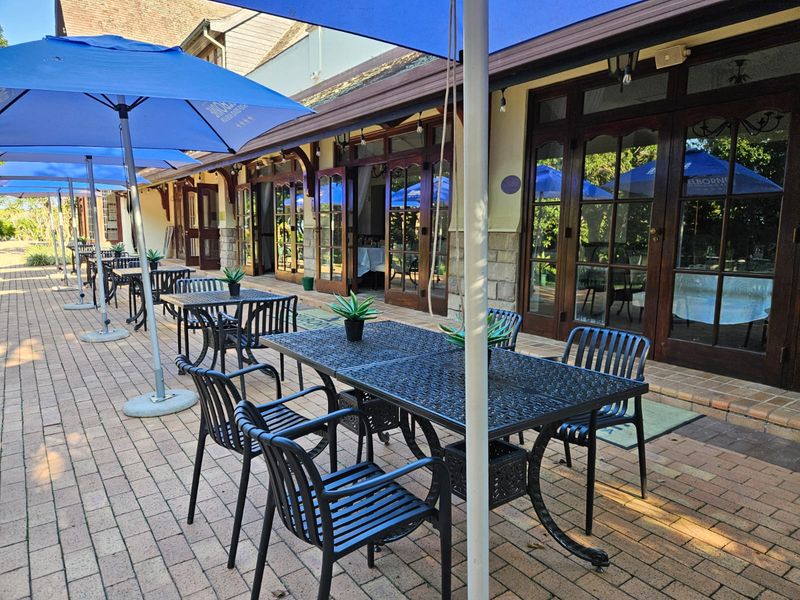 A spacious paved outdoor patio area featuring stone wall accents and multiple timber-framed glass doors providing access to the interior.