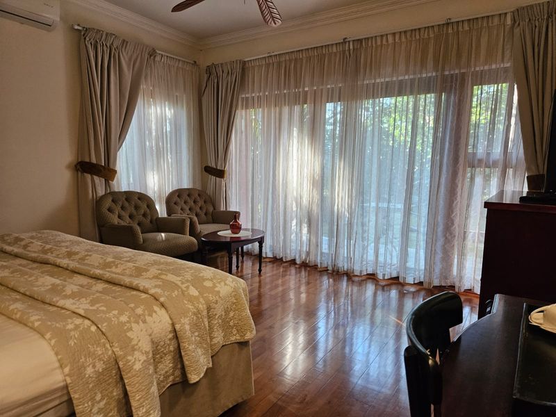 Spacious bedroom featuring polished hardwood flooring, crown molding, a ceiling fan, and large sliding glass doors providing ample natural light.