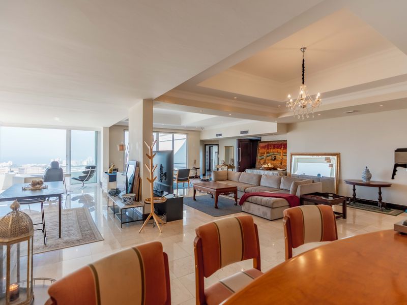 Spacious open-plan penthouse living area featuring high-end marble flooring, recessed ceilings, and expansive floor-to-ceiling windows offering panoramic city and coastal views.