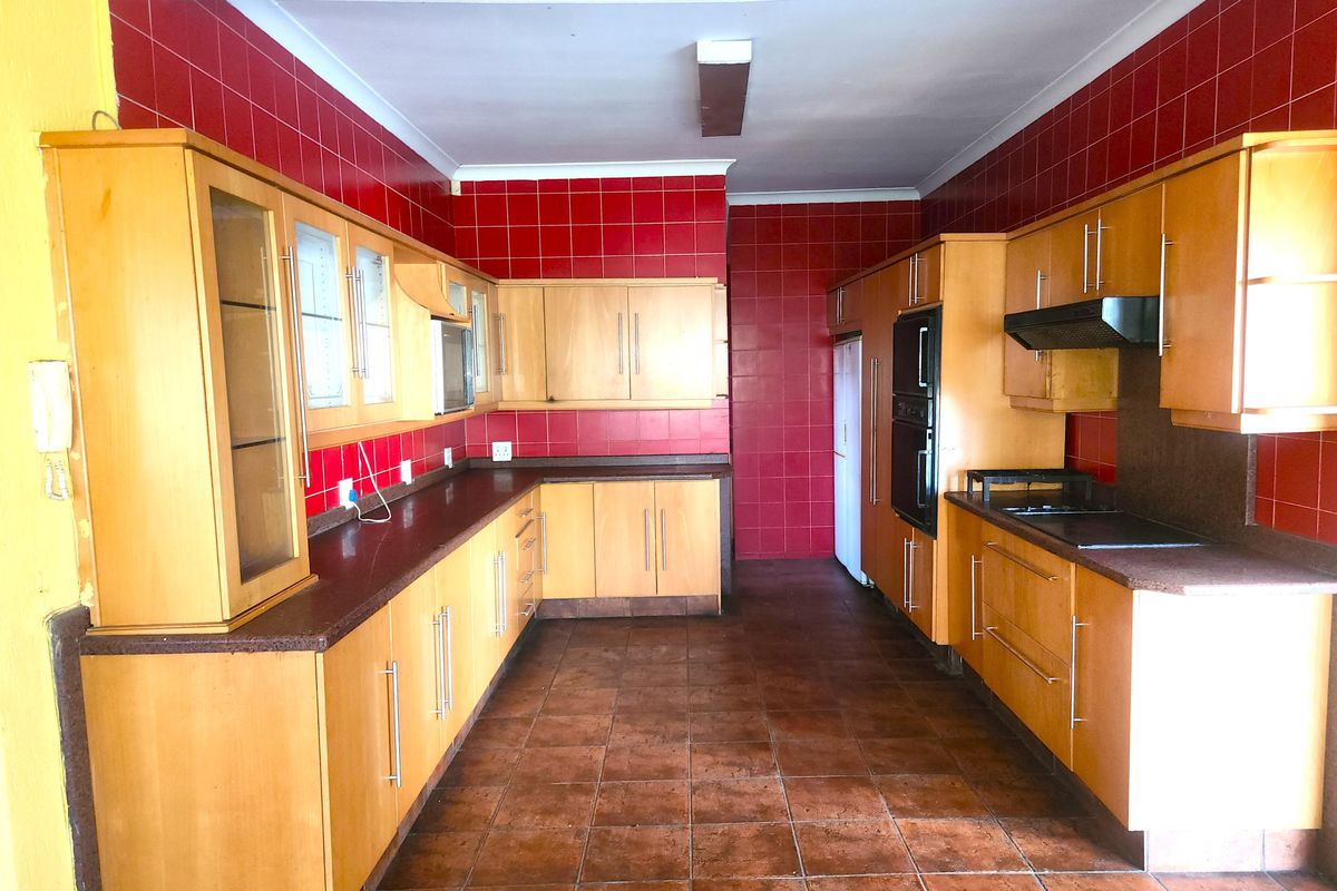 Spacious kitchen featuring extensive built-in cabinetry, tiled backsplash, and integrated appliances, offering a functional layout ready for modern updates.