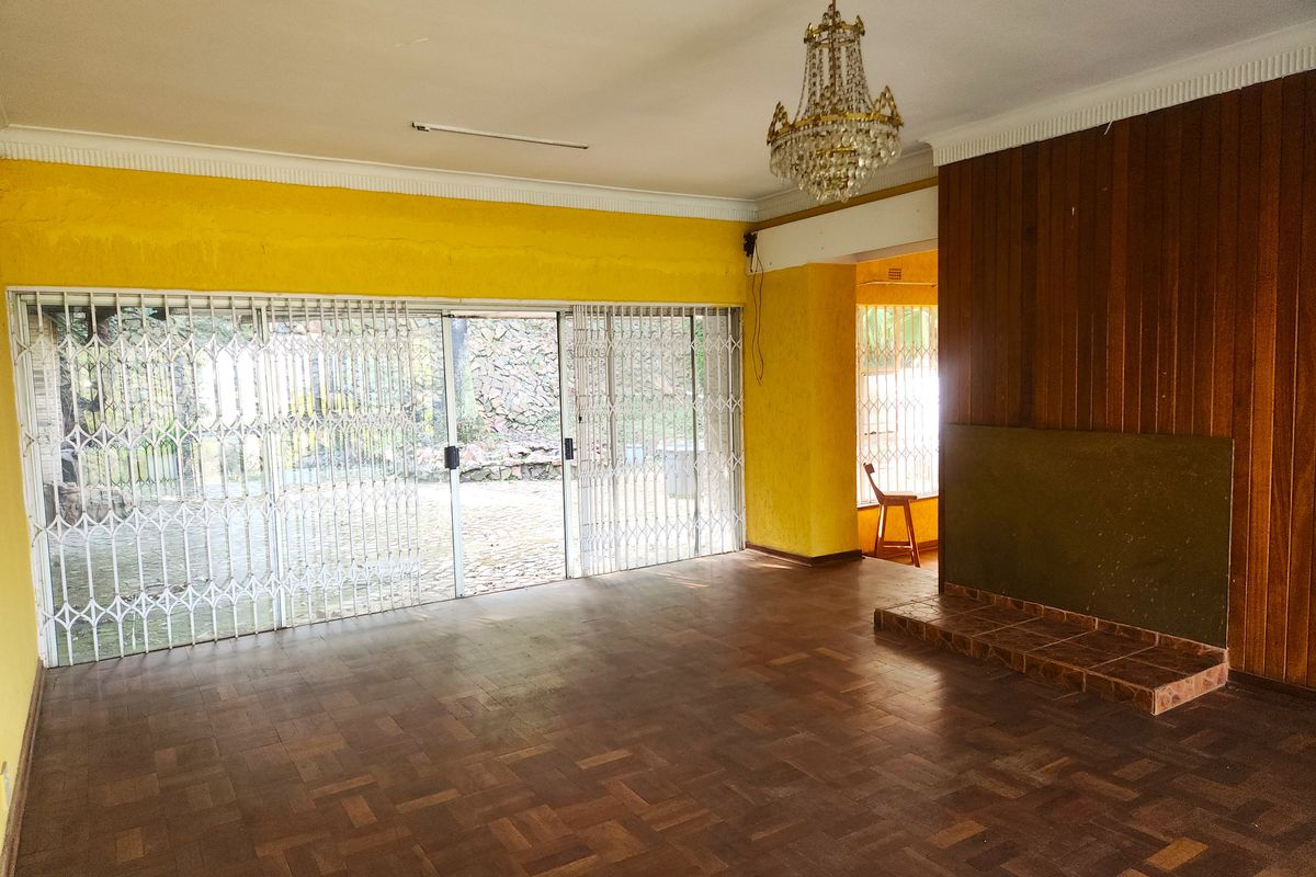 Spacious living room featuring original parquet flooring, a fireplace with wood paneling, and large sliding doors leading to the exterior.
