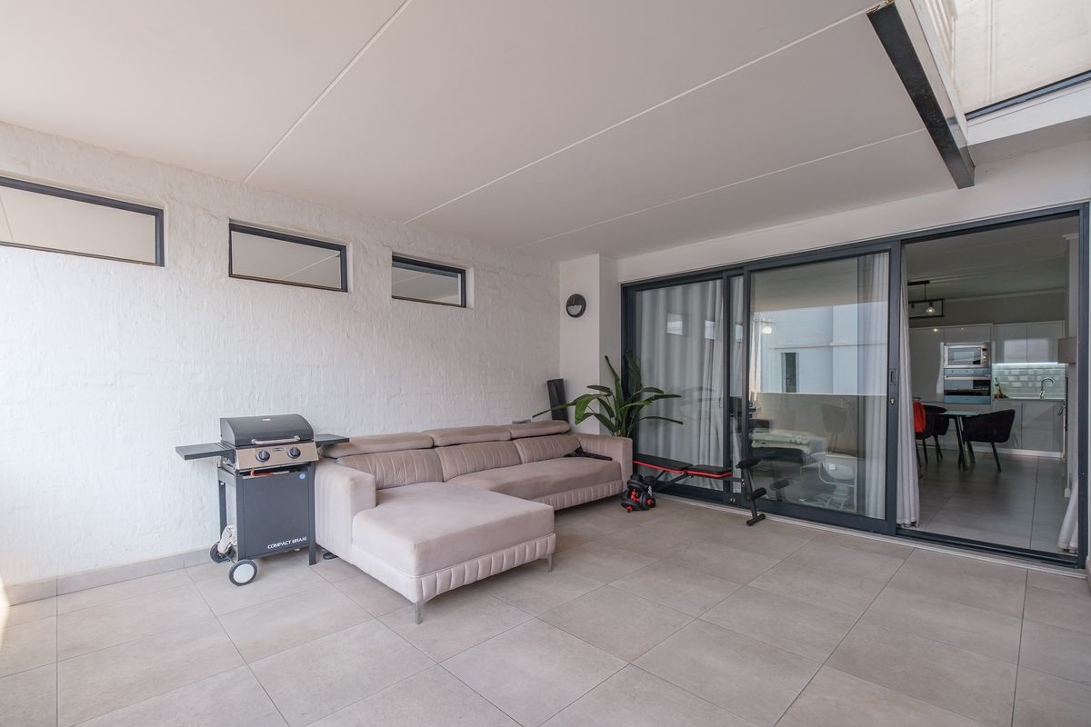 A covered patio area featuring tiled flooring, textured walls, and large sliding glass doors providing seamless access to the interior living space.