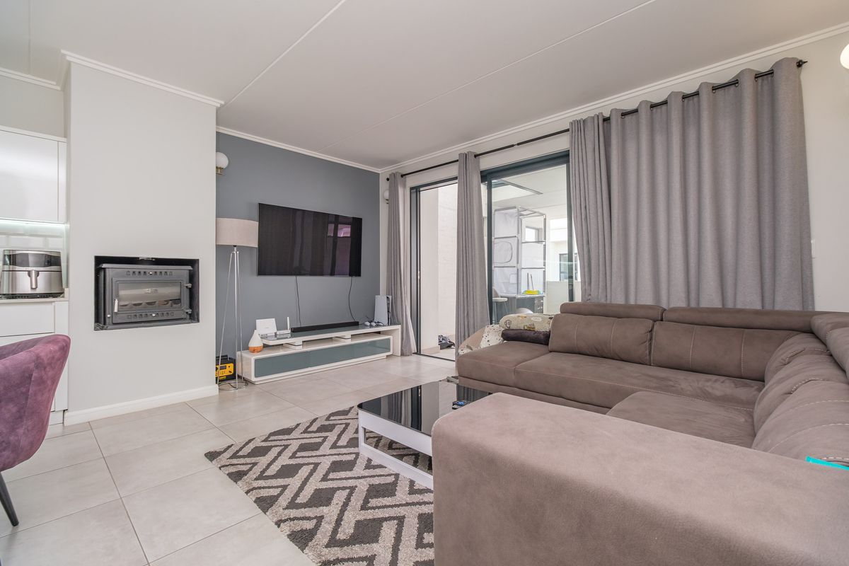 Modern living room featuring tiled flooring, a built-in fireplace, and large sliding glass doors providing access to the outdoor patio area.