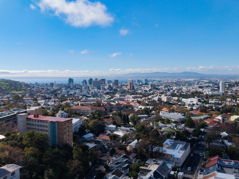 An expansive aerial view overlooking the suburban landscape and city skyline, showcasing the surrounding urban environment and coastal horizon.