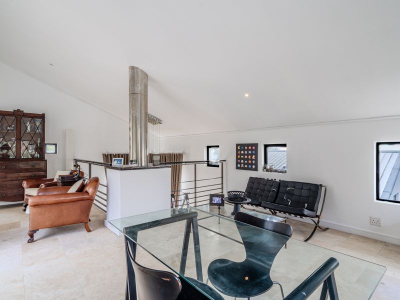 Spacious living area featuring vaulted ceilings, stone tile flooring, and a modern metal balustrade overlooking the lower level.