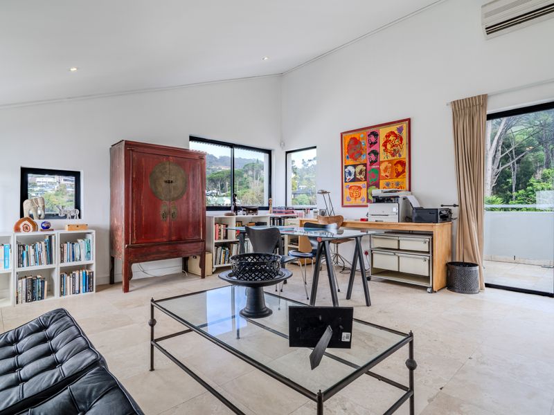 Spacious home office featuring tiled flooring, recessed lighting, split-system air conditioning, and large sliding glass doors providing access to an outdoor balcony.