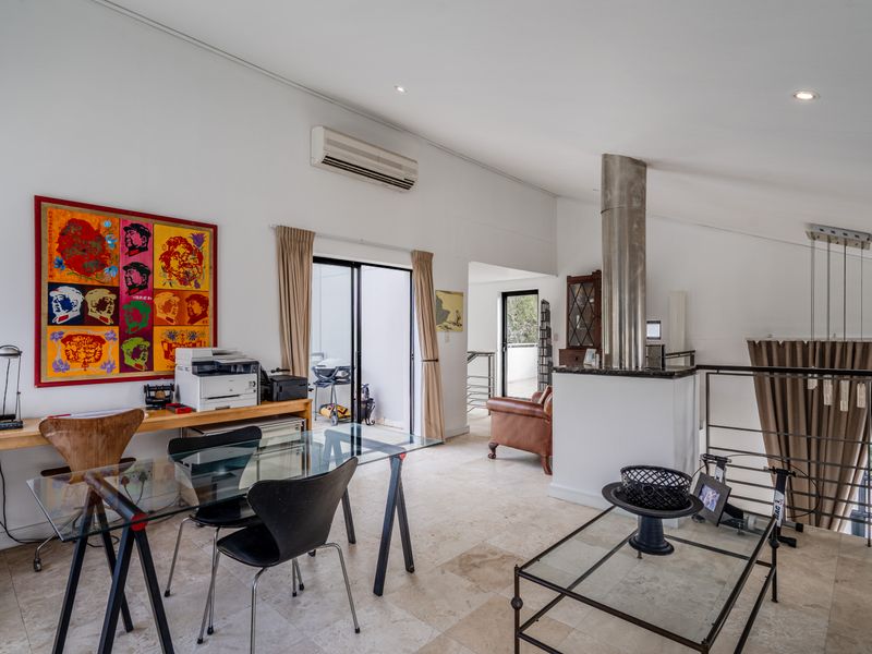 Spacious living area featuring stone tile flooring, a modern fireplace flue, and direct access to an outdoor balcony through sliding glass doors.