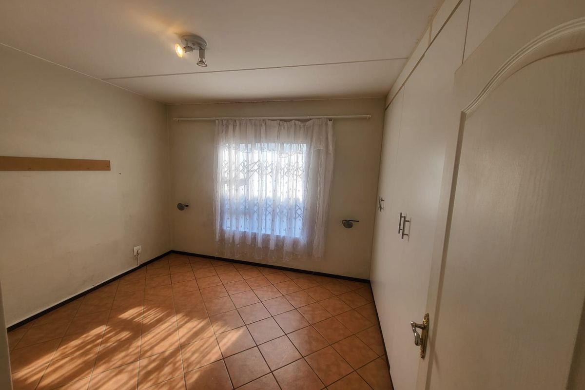 An empty bedroom featuring tiled flooring and built-in cupboards, offering a blank canvas for potential buyers.