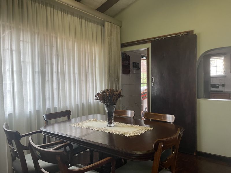 Dining room featuring parquet flooring, exposed ceiling beams, and a sliding door leading to an adjacent space.