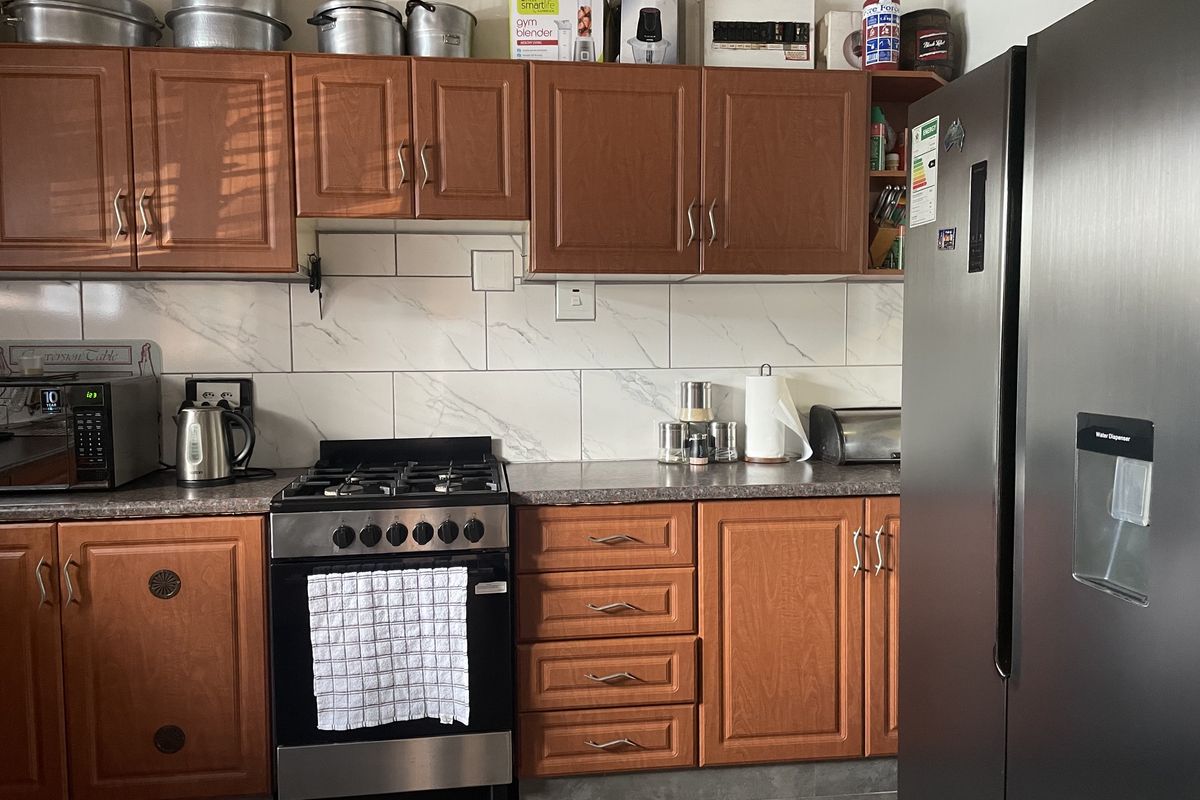 A functional kitchen featuring wooden cabinetry, marble-look subway tile backsplash, laminate countertops, and a built-in gas stove.