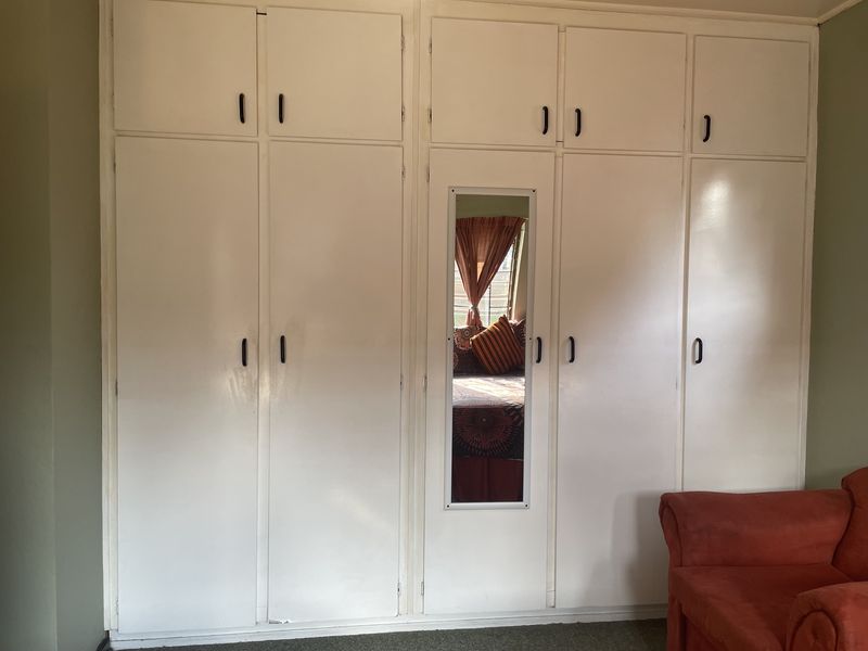 Bedroom featuring floor-to-ceiling built-in cupboards with an integrated central mirror, providing ample storage space.