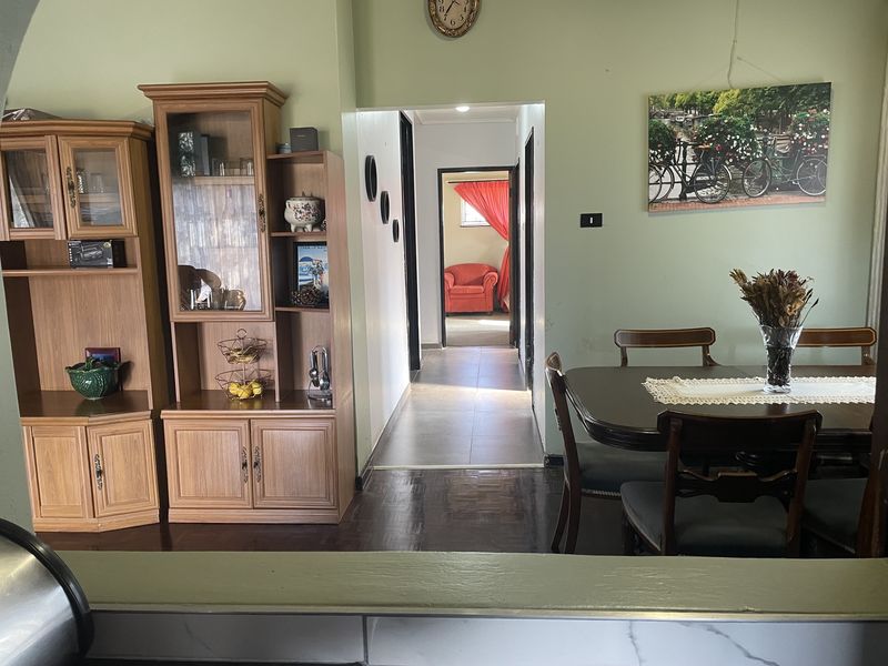 Dining area featuring parquet flooring and an open transition into a tiled hallway, providing a functional layout with potential for modern updates.