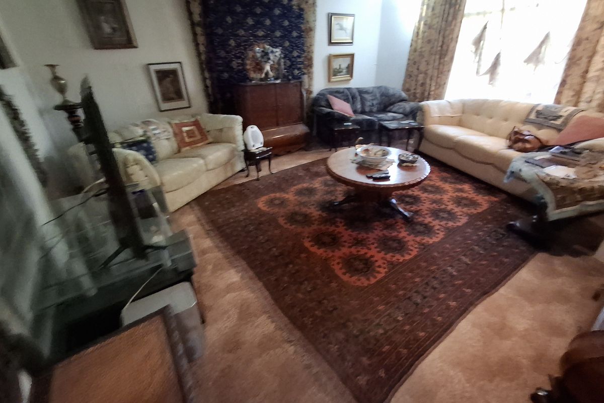 A spacious living room featuring a large window that allows for natural light, providing a comfortable and traditional living space.