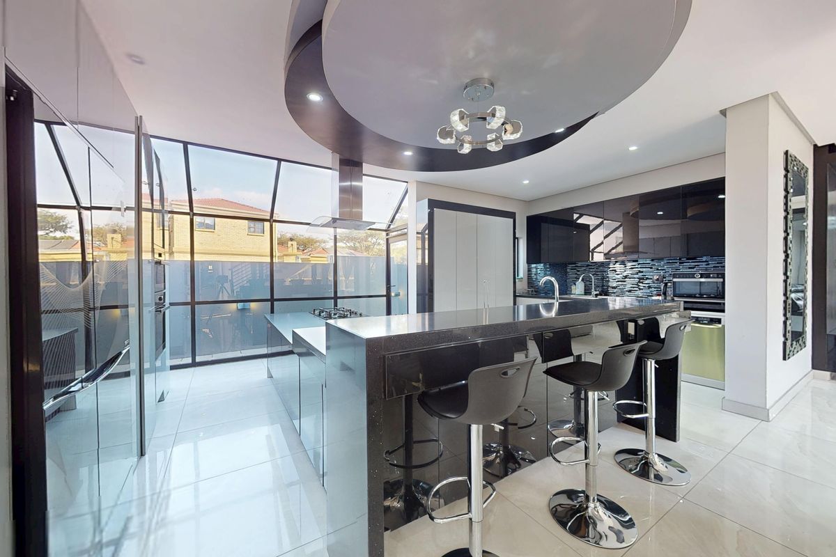 Modern kitchen featuring high-gloss cabinetry, a large central island with breakfast bar, integrated appliances, and a striking circular ceiling feature with recessed lighting.