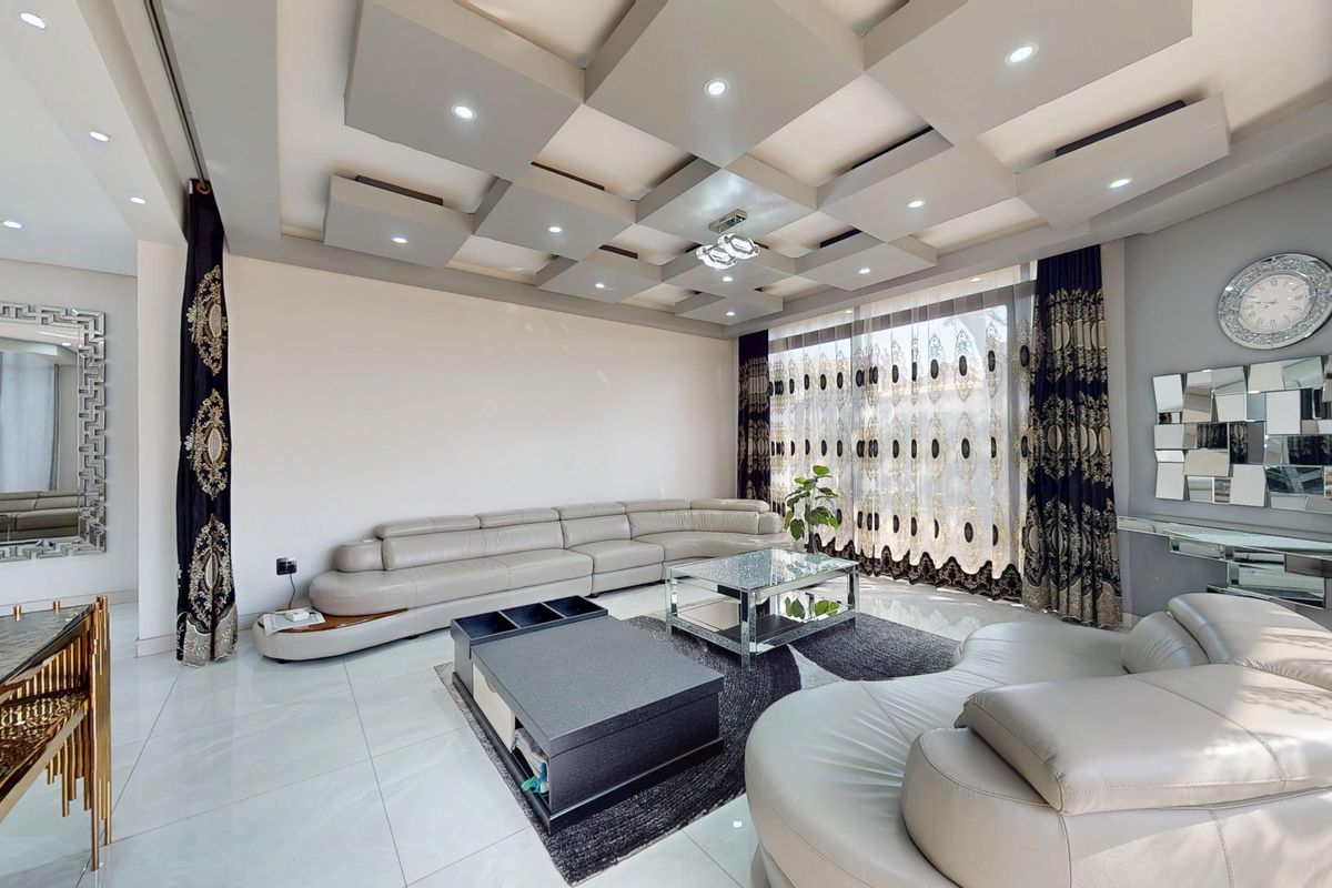 Spacious living room featuring a modern coffered ceiling with recessed lighting and large format polished floor tiles.