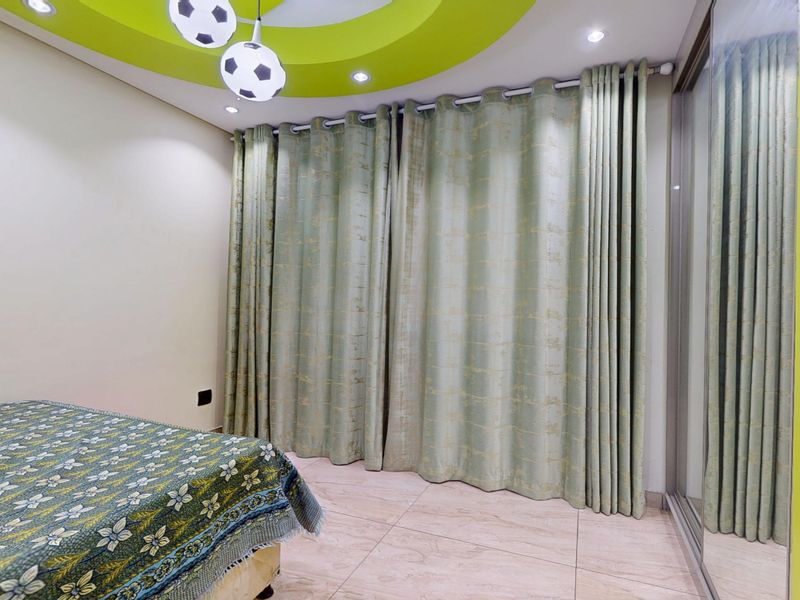 A bedroom featuring a recessed ceiling with decorative lighting, tiled flooring, and built-in mirrored sliding door wardrobes.