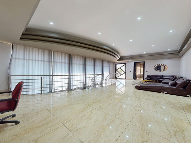 Spacious open-plan living area featuring polished marble-style floor tiles, recessed ceiling lighting, and a modern stainless steel balustrade overlooking the lower level.