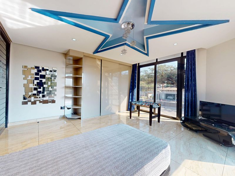 Spacious bedroom featuring large built-in wardrobes, tiled flooring, and a unique star-shaped ceiling feature with direct access to an outdoor balcony.