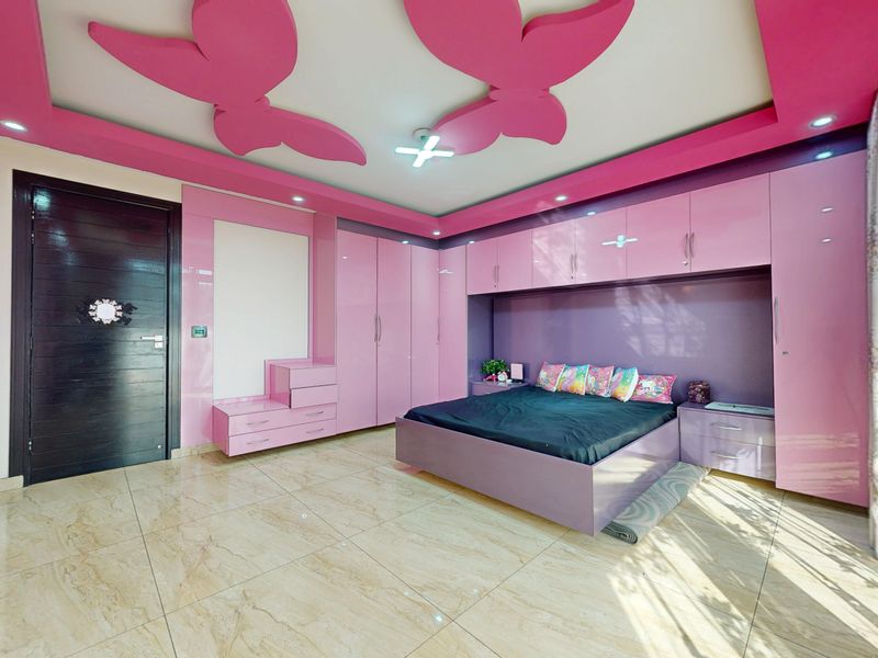 A vibrant bedroom featuring extensive built-in pink cabinetry, a custom butterfly-themed recessed ceiling design, and polished marble-look floor tiles.