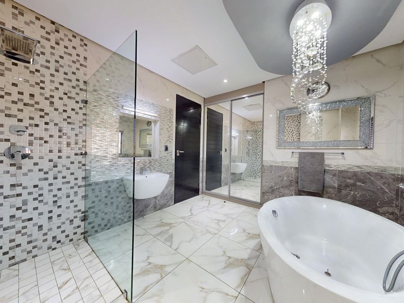 Modern luxury bathroom featuring a glass-enclosed walk-in shower, a freestanding soaking tub, marble-style floor tiles, and elegant decorative lighting.