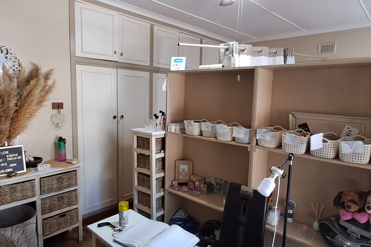 A functional room featuring built-in floor-to-ceiling cabinetry and a ceiling-mounted curtain track, currently utilized as a workspace.