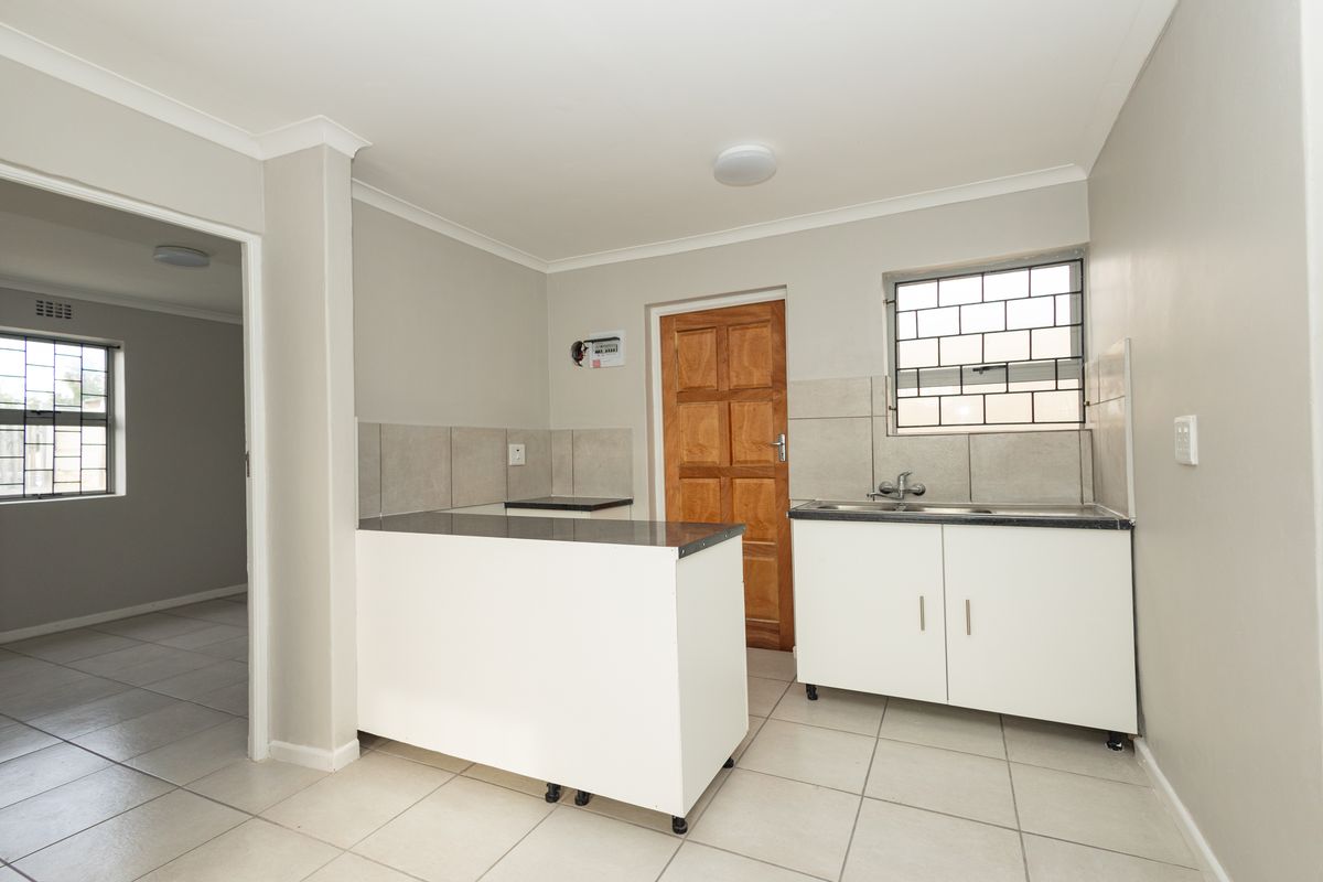 A functional, empty kitchen area featuring tiled flooring, built-in cabinetry with laminate countertops, and a stainless steel sink, ready for personalization.
