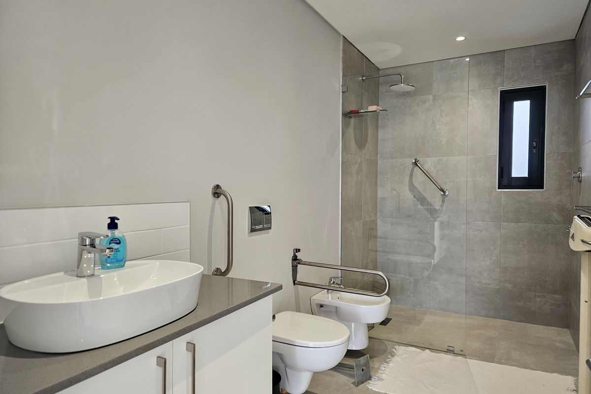 Modern bathroom featuring a walk-in shower with glass screen, wall-mounted toilet, bidet, and a contemporary vanity with a vessel sink.