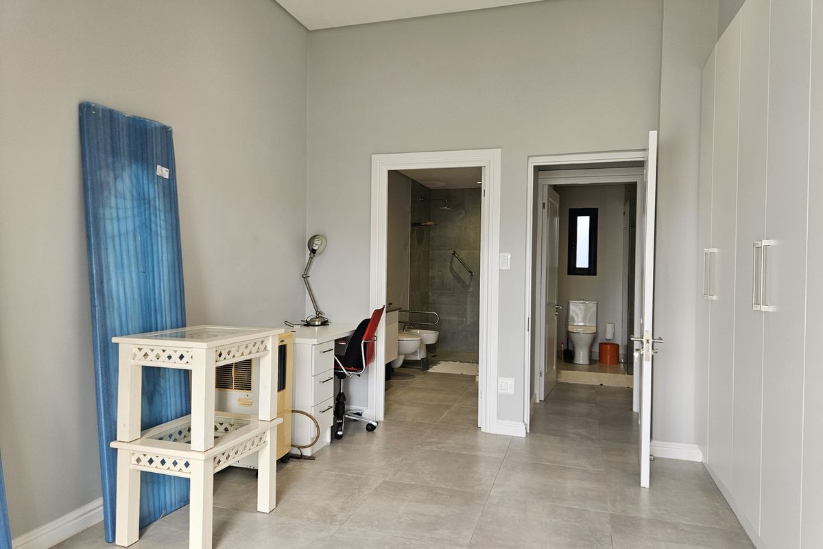 A bedroom featuring built-in cupboards, tiled flooring, and direct access to an en-suite bathroom with a shower and separate toilet area.
