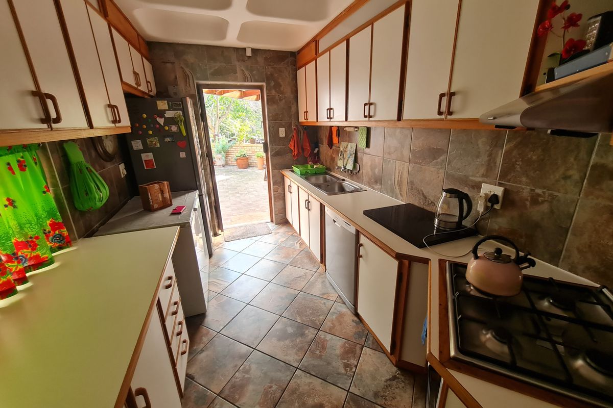 Functional galley-style kitchen featuring ample built-in cabinetry, dual cooking hobs, and direct access to the rear patio area.