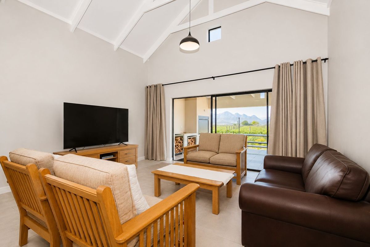 Spacious living room featuring high vaulted ceilings, tiled flooring, and large sliding glass doors opening to a covered patio with scenic mountain views.
