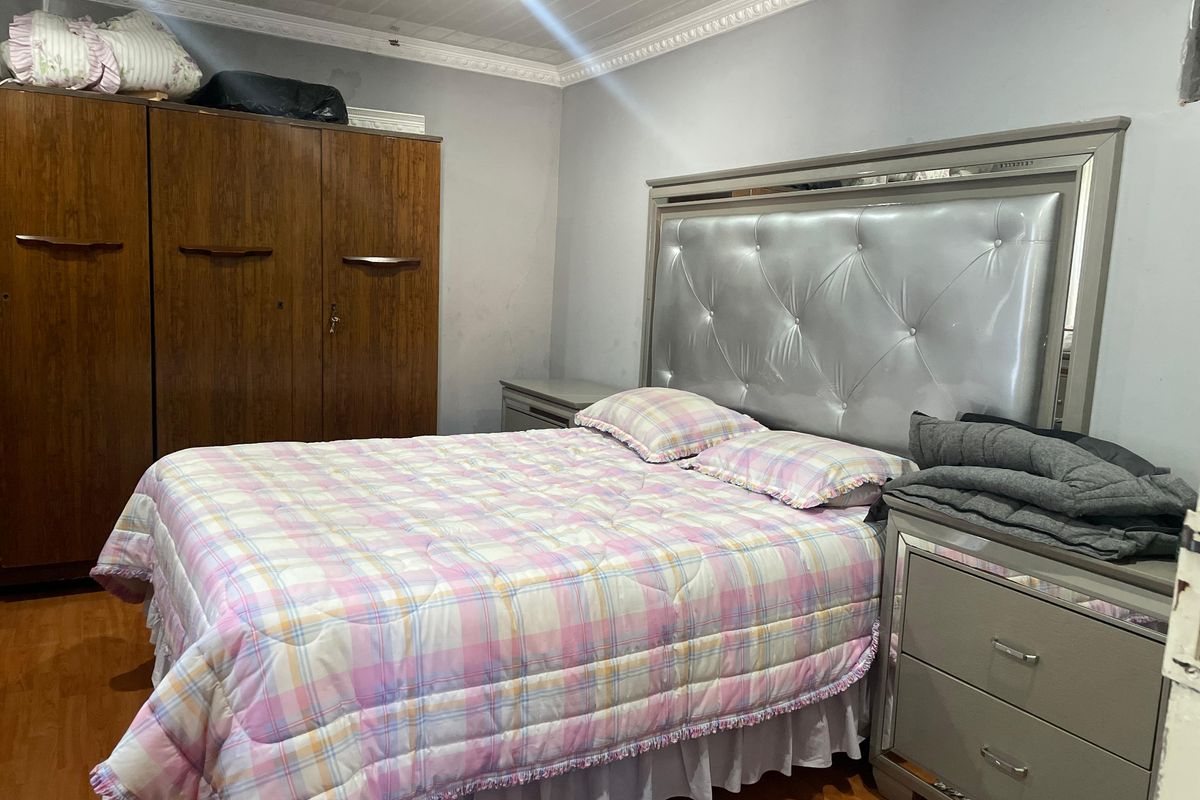 A bedroom featuring laminate flooring, crown molding, and a built-in wardrobe, offering a functional space with potential for cosmetic updates.
