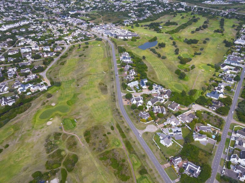 An aerial view of a residential estate featuring a golf course, surrounding homes, and established road infrastructure.