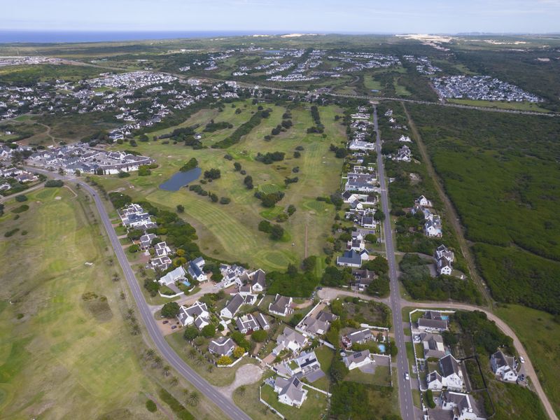 An aerial view of a residential estate integrated with a golf course, showcasing the surrounding landscape and neighborhood layout.