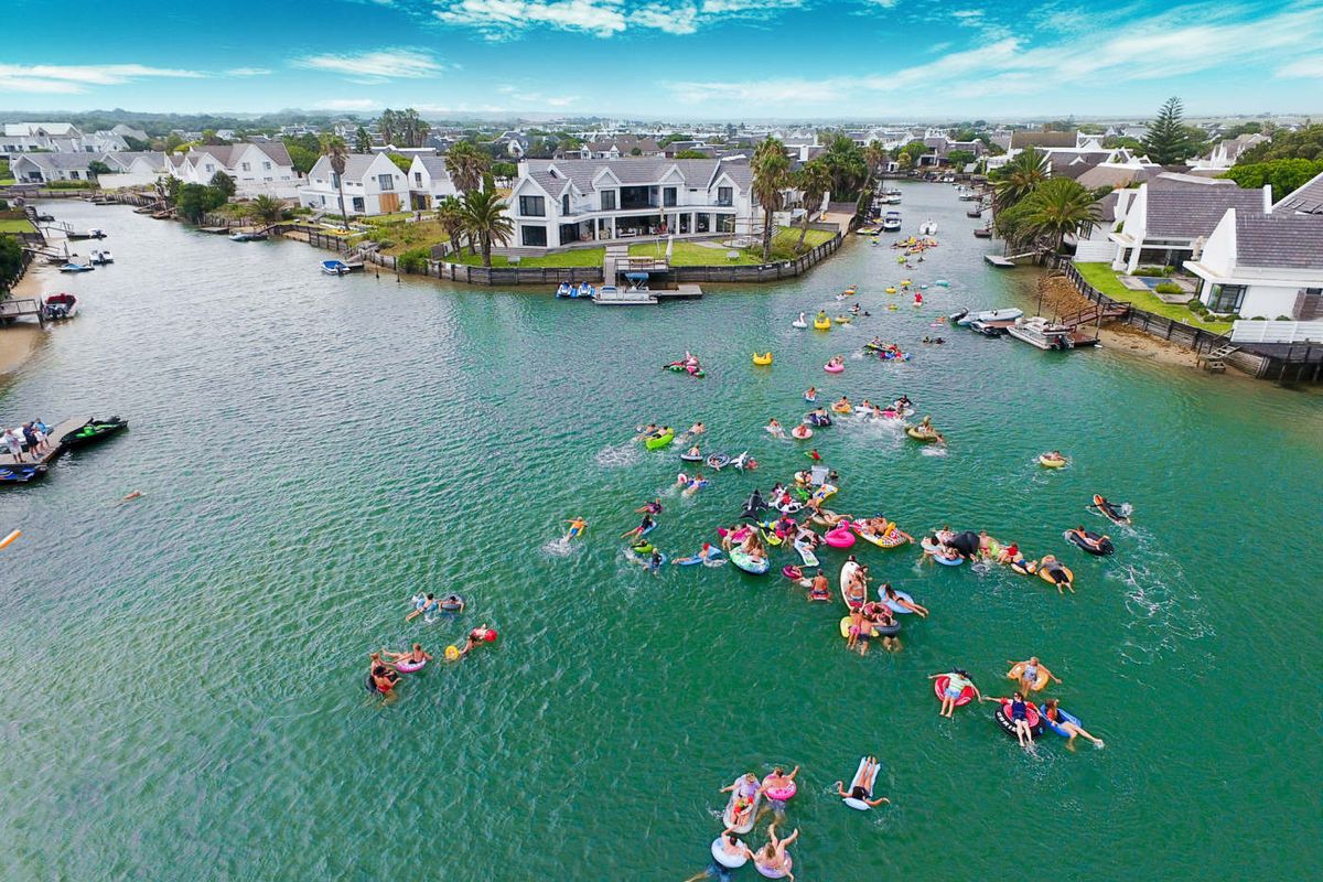 Aerial view of a residential waterfront estate featuring private jetties and landscaped gardens along a canal.