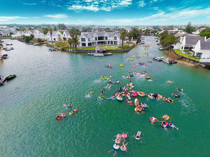 Aerial view of a residential waterfront estate featuring private jetties and landscaped gardens along a canal.