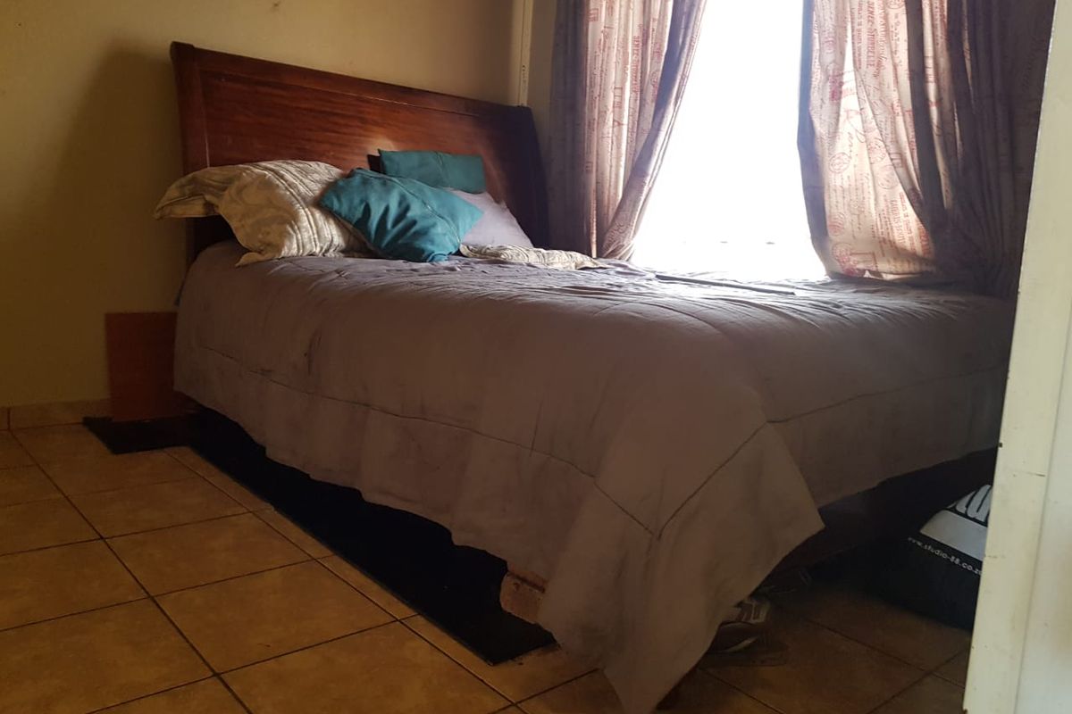 A bedroom featuring tiled flooring and natural light from a window, currently requiring cosmetic updates to improve the overall finish and appeal.
