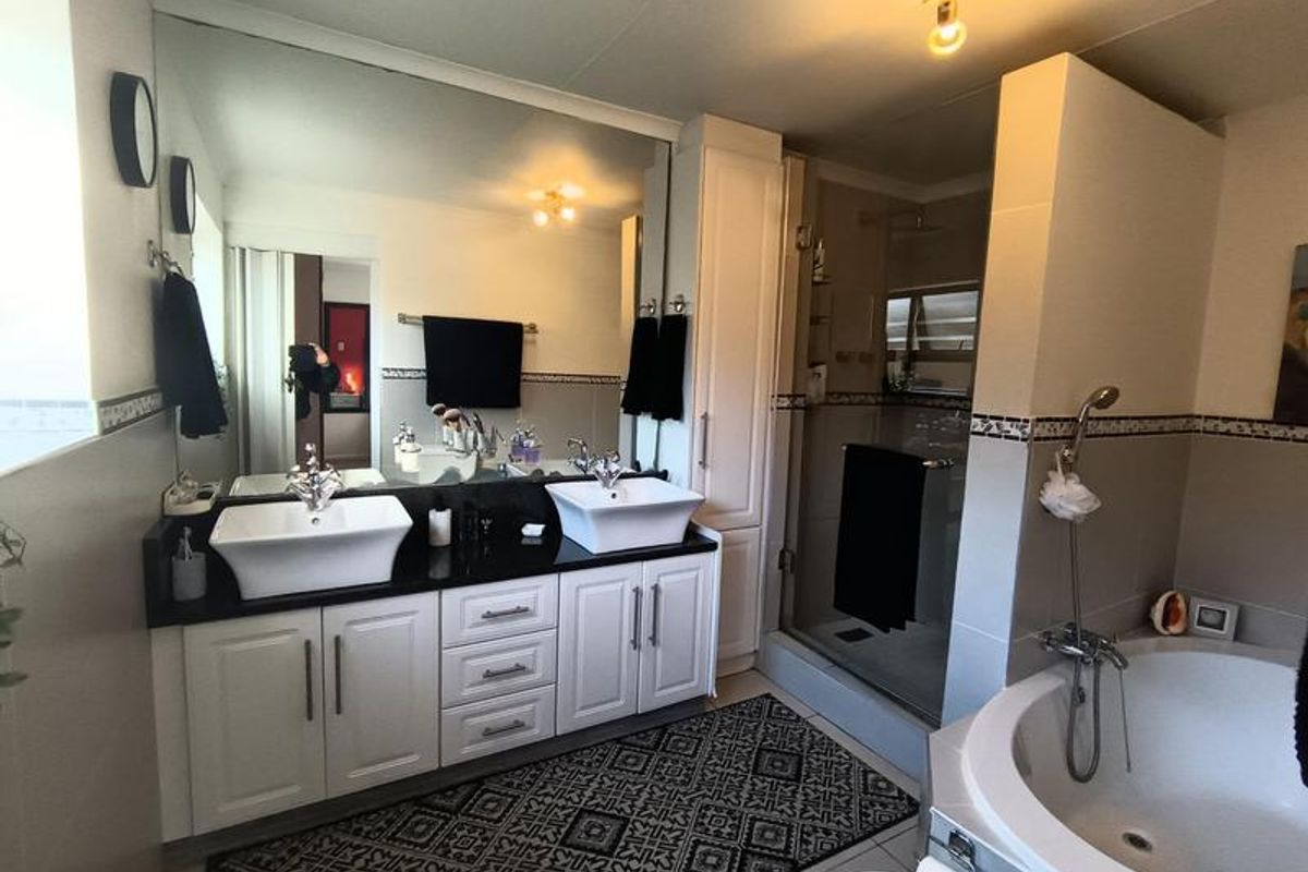 A well-appointed bathroom featuring a double vanity with vessel sinks, a large wall mirror, a separate glass-enclosed shower, and a built-in soaking tub.