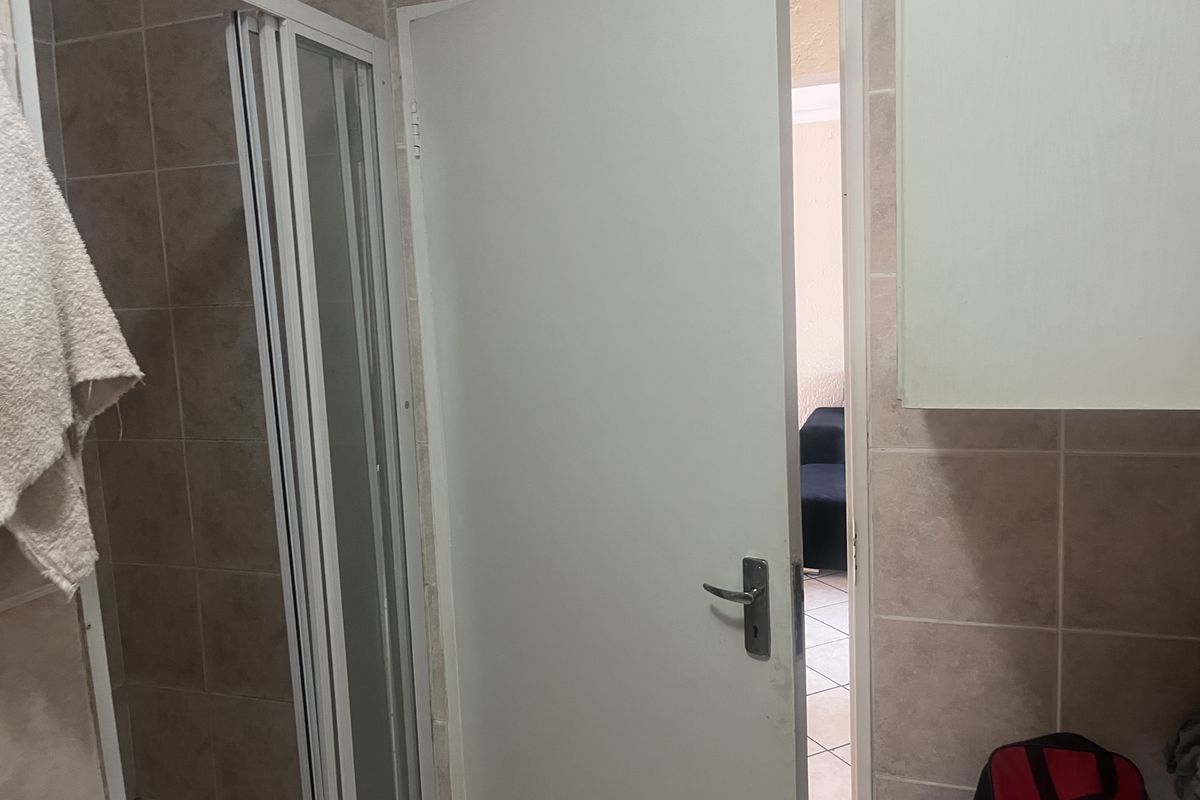 A functional bathroom featuring a shower enclosure with tiled walls and built-in cabinetry, providing essential utility space.