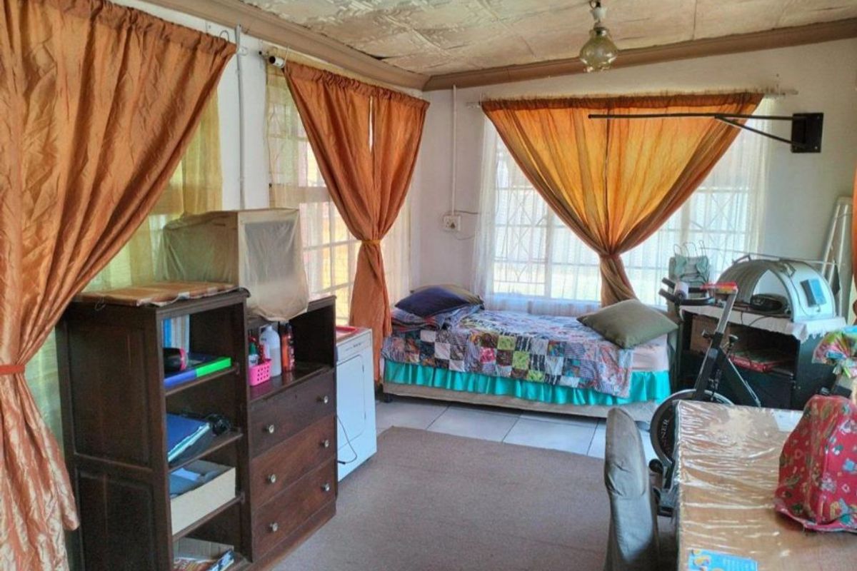 A bedroom featuring tiled flooring and textured ceiling tiles, equipped with security bars on the windows.