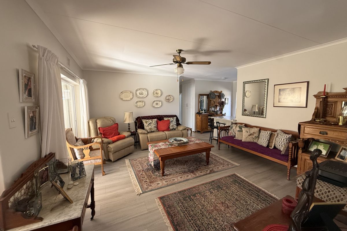 Spacious living area featuring light-toned laminate flooring, a central ceiling fan, and sliding glass doors providing access to the exterior.