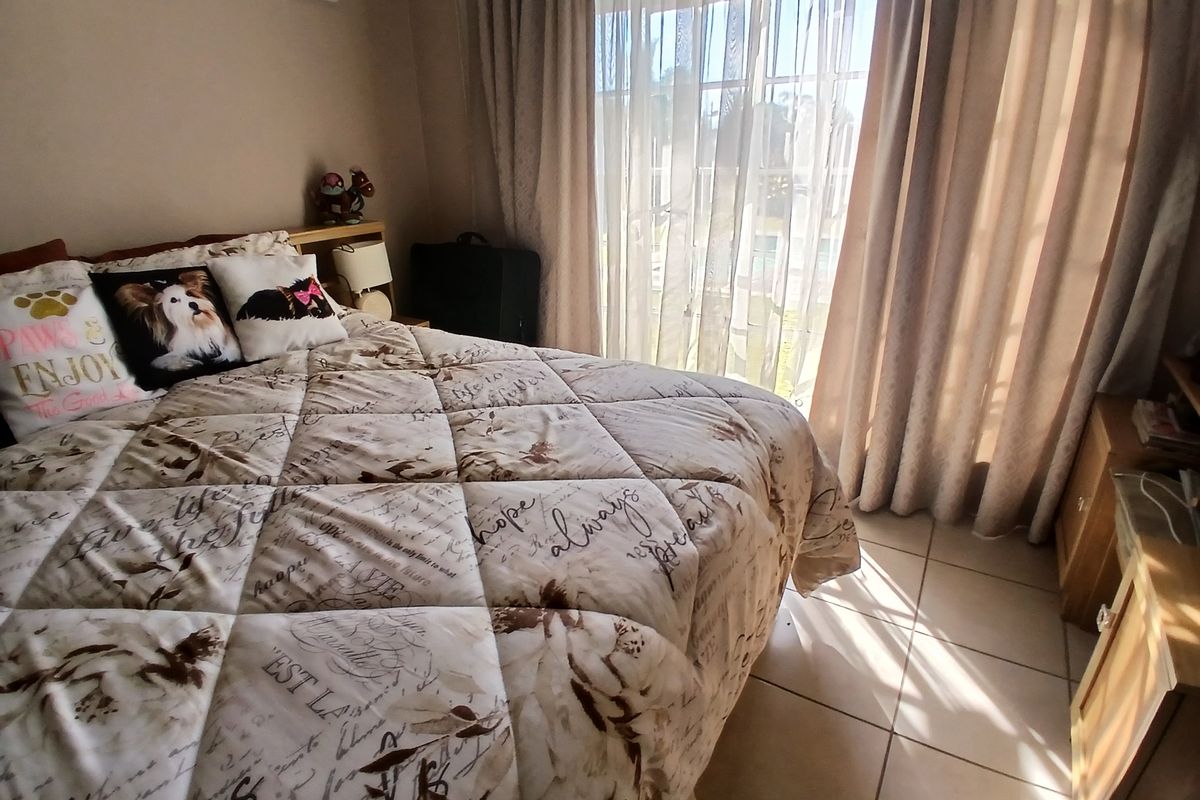 A bedroom featuring tiled flooring and a large sliding glass door that provides natural light and access to the exterior.