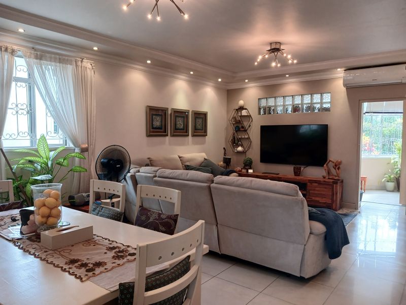 Spacious open-plan living and dining area featuring tiled floors, recessed ceiling lighting, decorative cove molding, and a wall-mounted split system air conditioner.