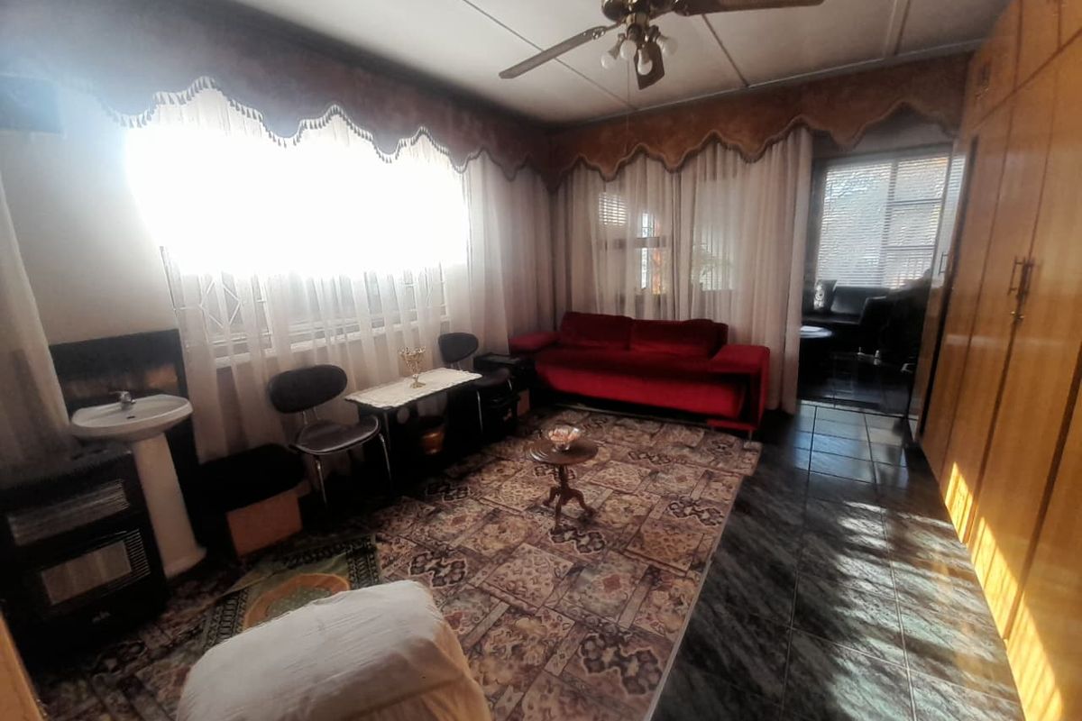 A living room featuring tiled flooring, a ceiling fan, and built-in storage cupboards, with a pedestal basin installed in the corner.