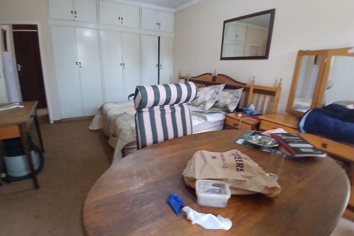 A bedroom featuring extensive built-in cupboards and carpeted flooring, offering a functional space with potential for modernization.