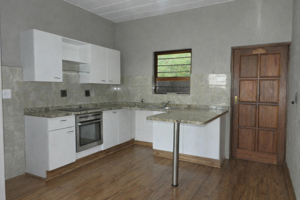 A functional kitchen featuring white cabinetry, granite countertops, a built-in oven, and a breakfast bar, finished with tiled splashbacks and laminate flooring.