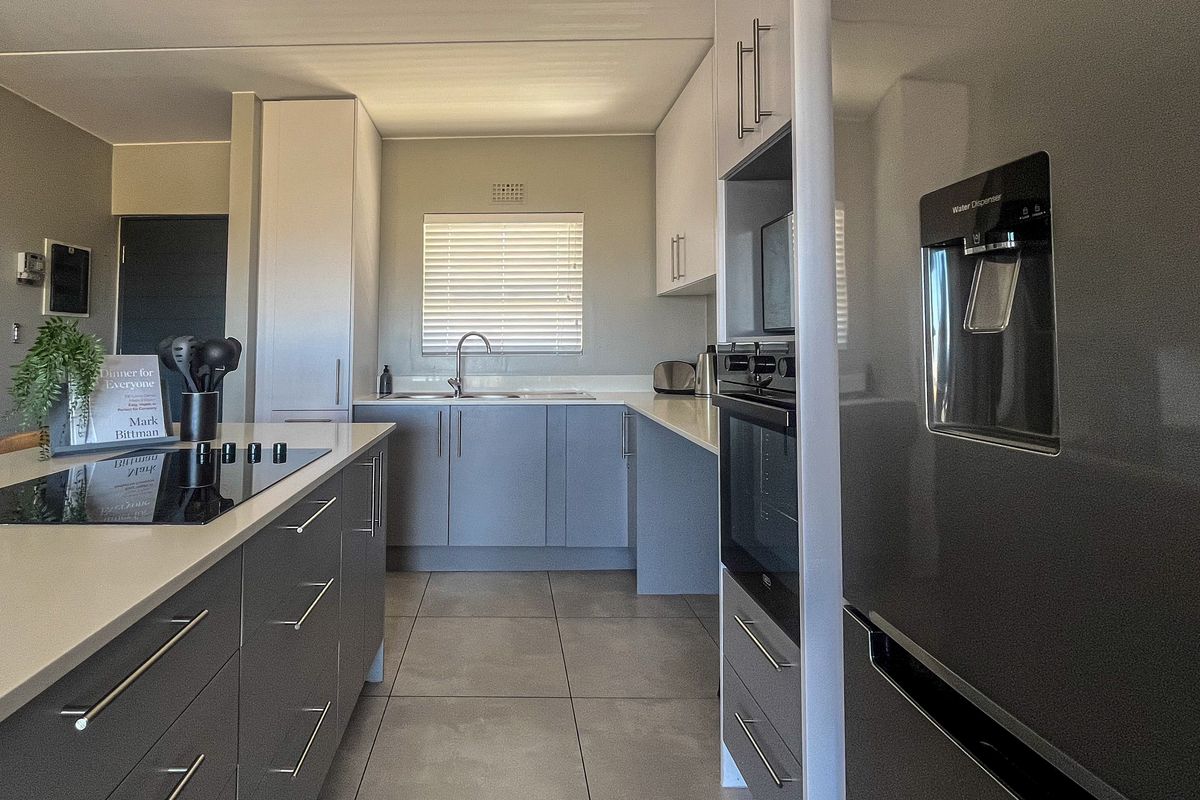 Modern kitchen featuring a central island with an induction hob, sleek cabinetry, built-in oven, and tiled flooring, offering a clean and functional workspace.