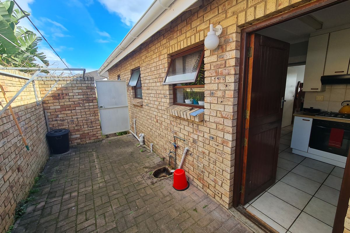 A rear exterior courtyard featuring brick paving and walling, with direct access into the kitchen area.