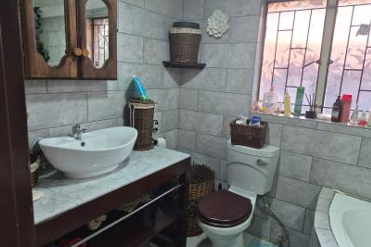 A functional bathroom featuring a vessel sink on a wooden vanity, a standard toilet, and a bathtub with tiled wall finishes.